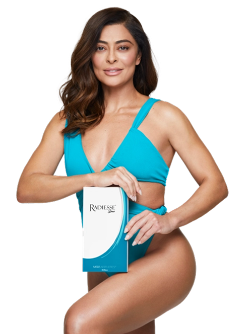 Mulher de cabelo longo e ondulado castanho, sorrindo, vestindo biquíni azul-turquesa. Ela segura sobre a perna uma caixa do produto Radiesse. Fundo branco.